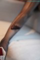 A close up of a woman's legs wearing black stockings and red shoes.