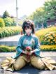 A woman in a kimono sitting on the ground holding a bouquet of flowers.