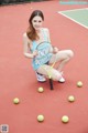 A woman kneeling on a tennis court holding a tennis racket.