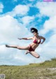 A woman in a red bikini jumping in the air.