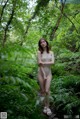 A woman in a bathing suit standing in the woods.