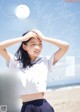 A woman in a white shirt and blue skirt on a beach.