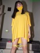 A woman wearing a yellow dress and a face mask.