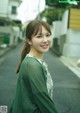 A woman in a green cardigan standing on a street.