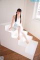 A young ballerina sitting on a white staircase in a room.