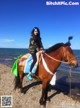 A woman riding on the back of a brown horse.