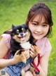 A young girl holding a small dog on a leash.