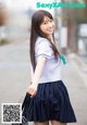 a japanese girl in a school uniform is walking down the street