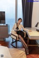 A woman sitting at a desk in front of a television.