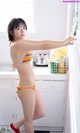 A woman in a bikini standing in a kitchen.