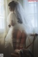 A woman in a wedding dress sitting on a chair.