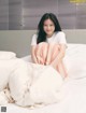 A woman sitting on top of a bed covered in white sheets.