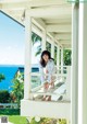 A woman sitting on a porch looking out at the ocean.