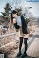 A woman standing on a sidewalk holding a cup of coffee.