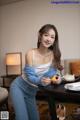 A woman sitting at a table holding an orange.