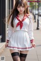 A woman in a white and red school uniform is walking down the street.