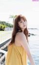 A woman in a yellow dress standing by the water.