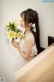 A woman in a white dress holding a bouquet of flowers.