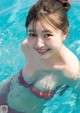 A young woman in a swimming pool smiling at the camera.