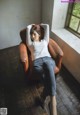 A woman sitting in a brown chair in front of a window.