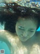 A woman swimming underwater with her hair blowing in the wind.