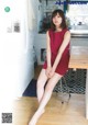 A woman in a red dress sitting on a stool in a kitchen.