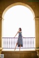 A woman in a blue dress standing on a balcony.