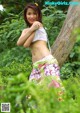 A woman in a white top and floral skirt posing for a picture.